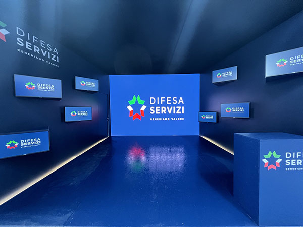 Key Comunicazione per Difesa Servizi ha progettato e realizzato uno stand di 25 mq in occasione dell’ottava edizione del Seafuture. Uno stand, in realtà un’istallazione con audiovisivi, dove è stata più importante la presenza del “software” che dell’”Hardware”. Nell'immagine sce una perspectiva dell'area decorata con muri portanti di diversi monitor che riflettono immagini in cui predomina il conlore blu. Nella parete del fondo una maxi schermo proetta il logo di Difesa Servizi con lettere bianche e il pittogramma in colori verde, bianco e rosso.
