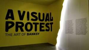 A VISUAL PROTEST. The art of Banksy Banksy, artista e writer inglese la cui identità rimane tuttora nascosta, è considerato uno dei maggiori esponenti della street art contemporanea. Le sue opere sono spesso connotate da uno sfondo satirico e trattano argomenti universali come la politica, la cultura e l’etica. Allestimento in in cui sono stati utilizzati i colori giallo e bianco per mettere in risalto le opere dell'artista. per Key Comunicazione.