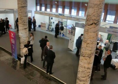 Allestimento di oltre 90 stand dell'Albergatore Day 2025. Visuale aerea del cortile del Palazzo dei congressi. in fondo la parete a vetro allestita con degli stand realizzati da Key Comunicazione in occasione dell' Albergatore Day 2025, organizzato da Federalberghi Roma. In primo piano 3 imponenti colonne di marmo.