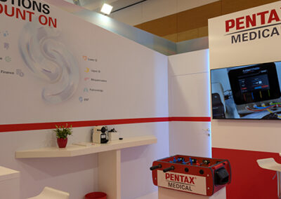 Progettazione Stand Aziendale per Congresso Medico con Key Comunicazione. Scopri il progetto Pentax e contattaci per il tuo evento Ecco lo stand Pentax Medical al Congresso FISMAD – progetto realizzato da Key Comunicazione. Inquadratura laterale che mostra la parete con grafiche tematiche legate ai servizi offerti (Training, Finance, Hygiene, ecc.). Il calcio balilla rosso con logo aziendale aggiunge un tocco inaspettato. Il bancone laterale, corredato da macchina per il caffè e pianta verde, sottolinea l’attenzione all’accoglienza. L’insieme degli elementi riflette una progettazione stand fieristici orientata alla relazione.