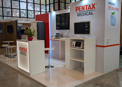 Vista angolare dello stand Pentax Medical a cura di Key Comunicazione, con grafiche istituzionali, aree espositive ordinate e pavimento bianco.