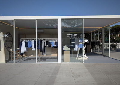 Vista frontale esterna dello stand Oysho by Key Comunicazione. Due moduli espositivi in vetro con struttura modulare e linee essenziali. Manichini visibili dall’esterno, espositori ordinati e logo Oysho in vetrofania. Integrazione perfetta con l’ambiente outdoor.