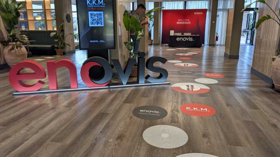 Sala convention Enovis con LED wall K.K.M. Knee Kinematics Meeting e tavoli con coprisedie brandizzati, Roma 2026.