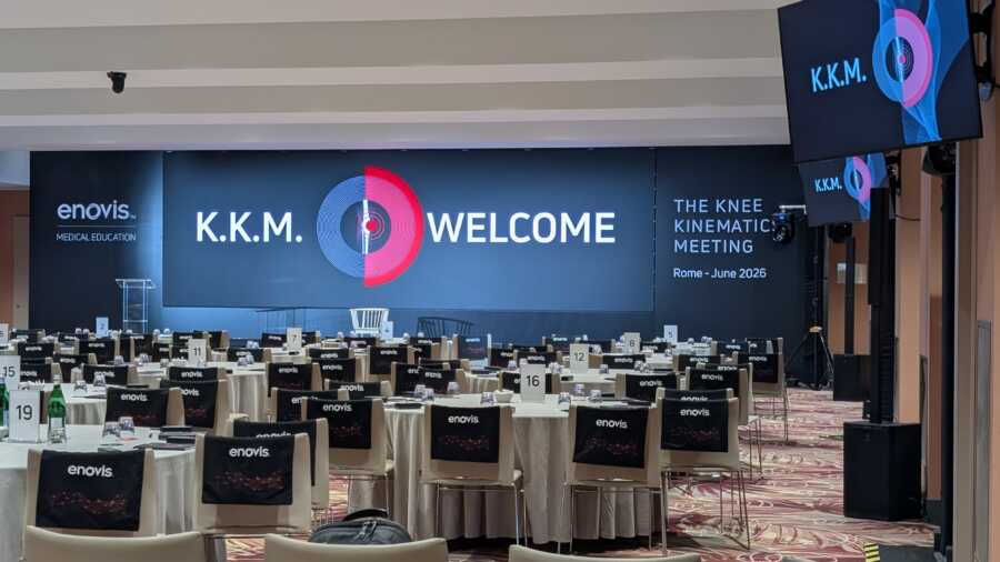 Sala convention Enovis con LED wall K.K.M. Knee Kinematics Meeting e tavoli con coprisedie brandizzati, Roma 2026.