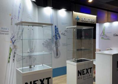 Stand Next Medical e Acumed con teche espositive, grafiche ortopediche su fondo chiaro e volume in legno listellare al Trauma Meeting di Riccione