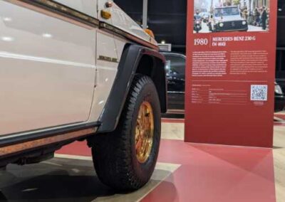 Dettaglio della Papamobile 230 G del 1980 con cerchio dorato e totem con foto storica di Giovanni Paolo II